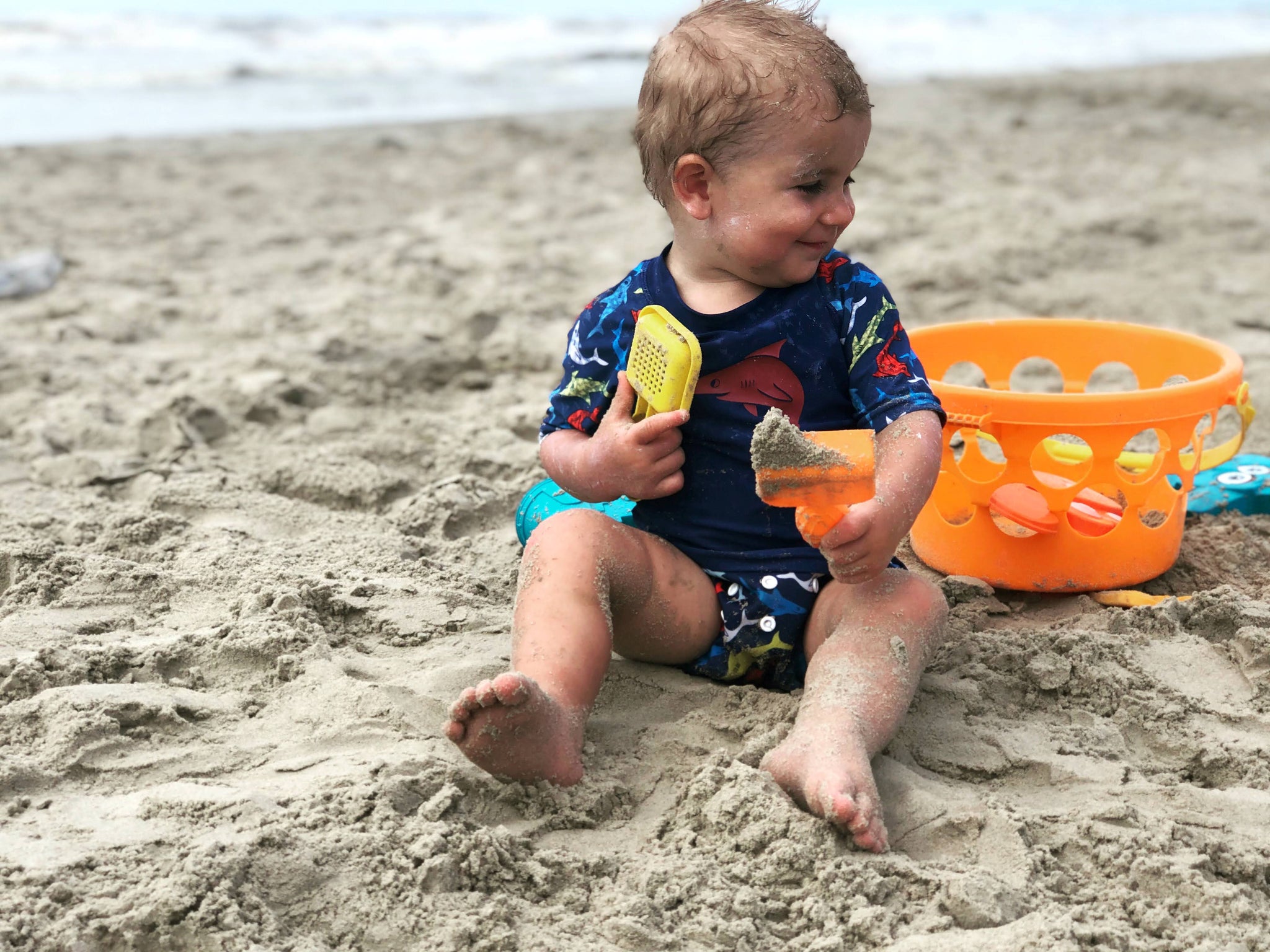 Happy kid playing in the sand at the beach