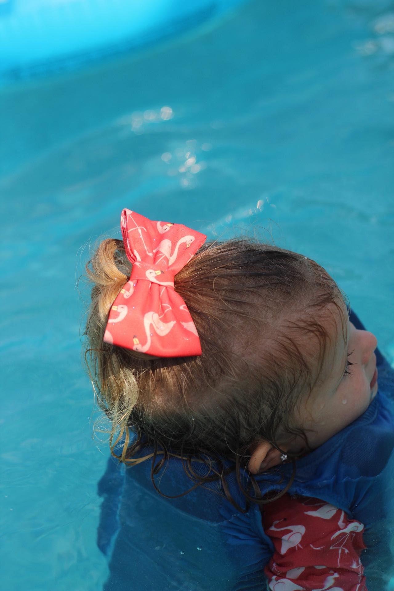 child swimming with her flamingo swimsuit