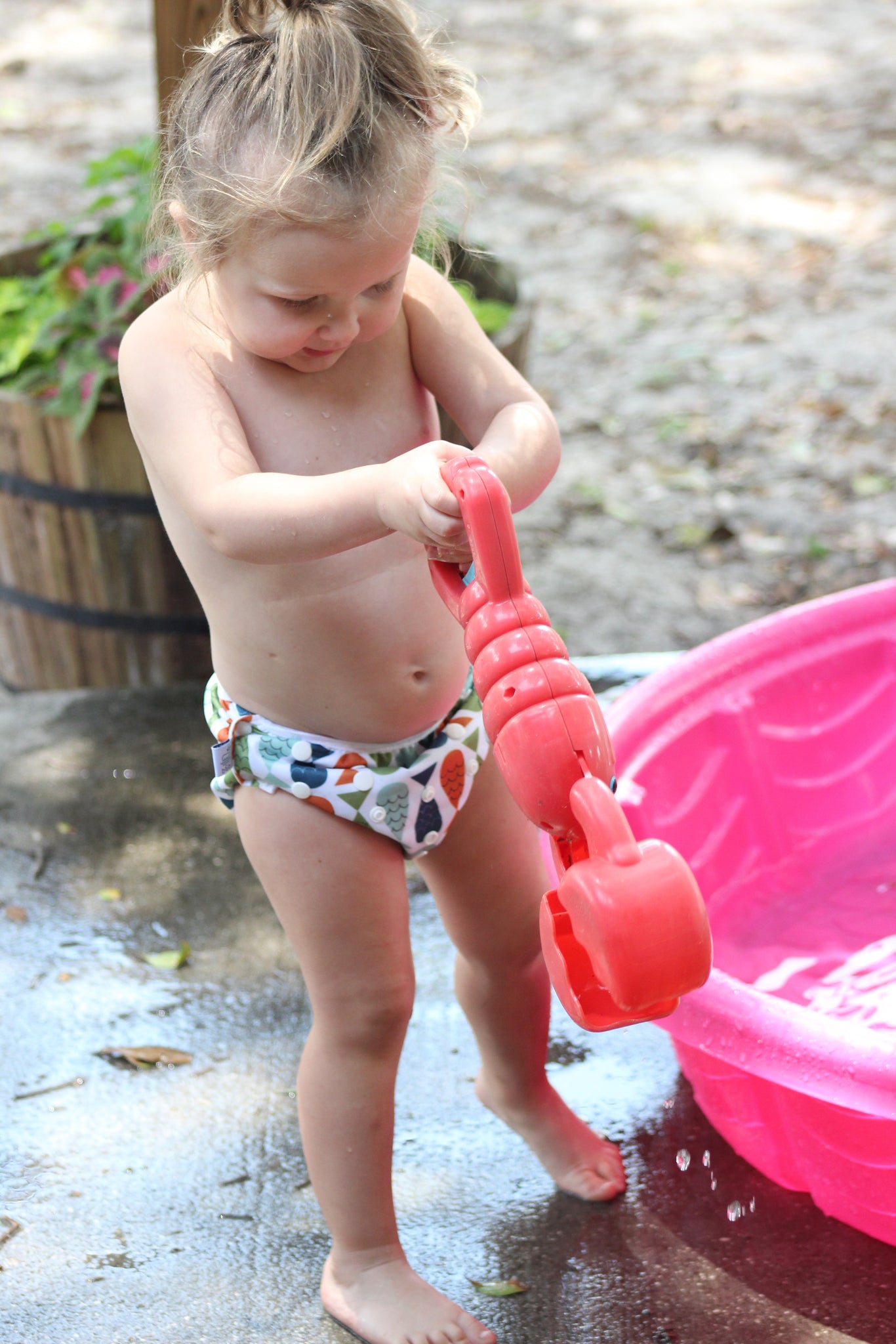 little girl wearing a Beau and Belle Littles Swim Diaper, Regular Size, fish print and playing at a kiddie pool