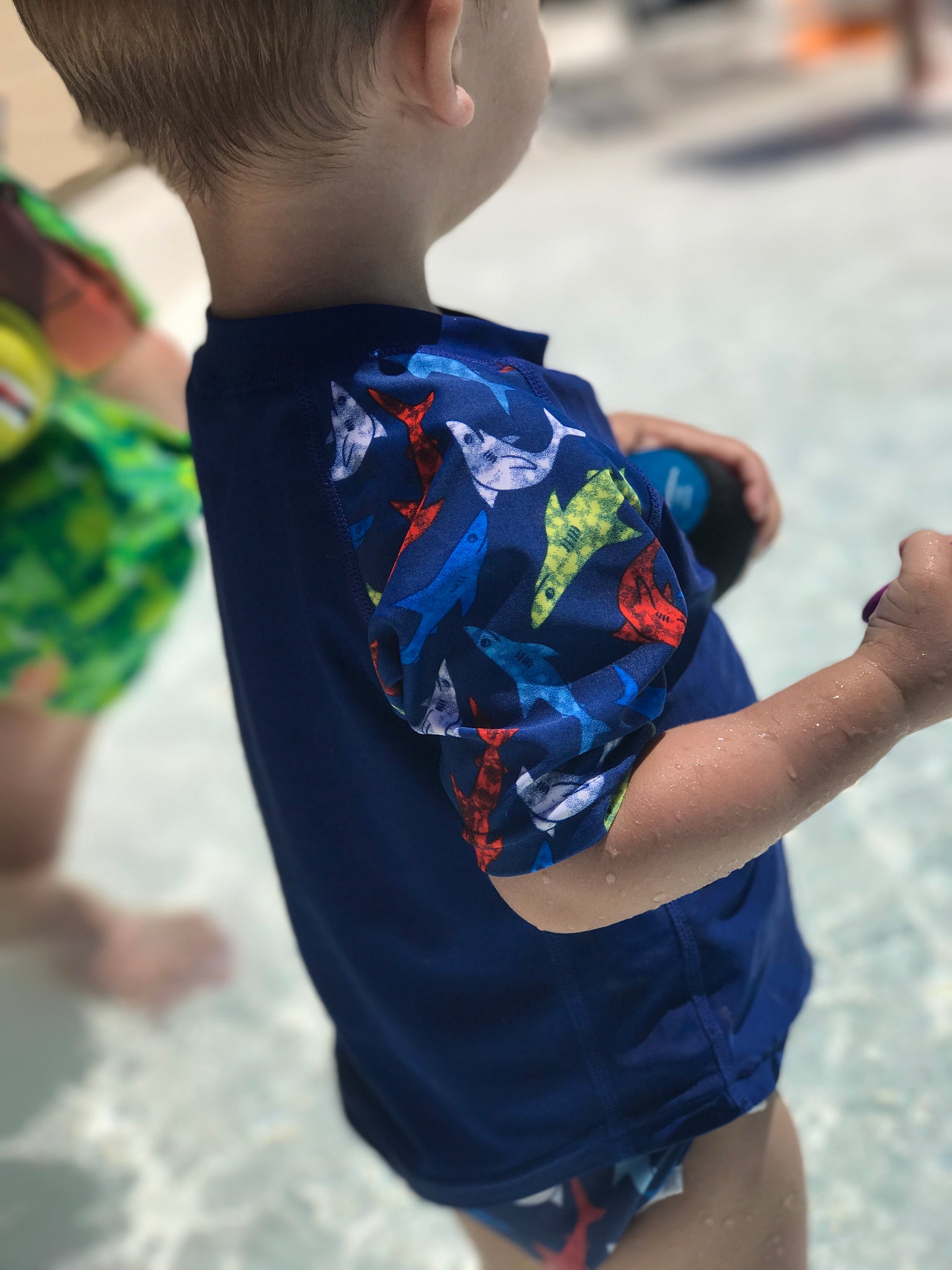 toddler boy wearing a Beau and Belle Littles Rash Guard/Swim Shirt, dark blue with lighter blue 3/4 sleeves, shark print and matching swim diaper