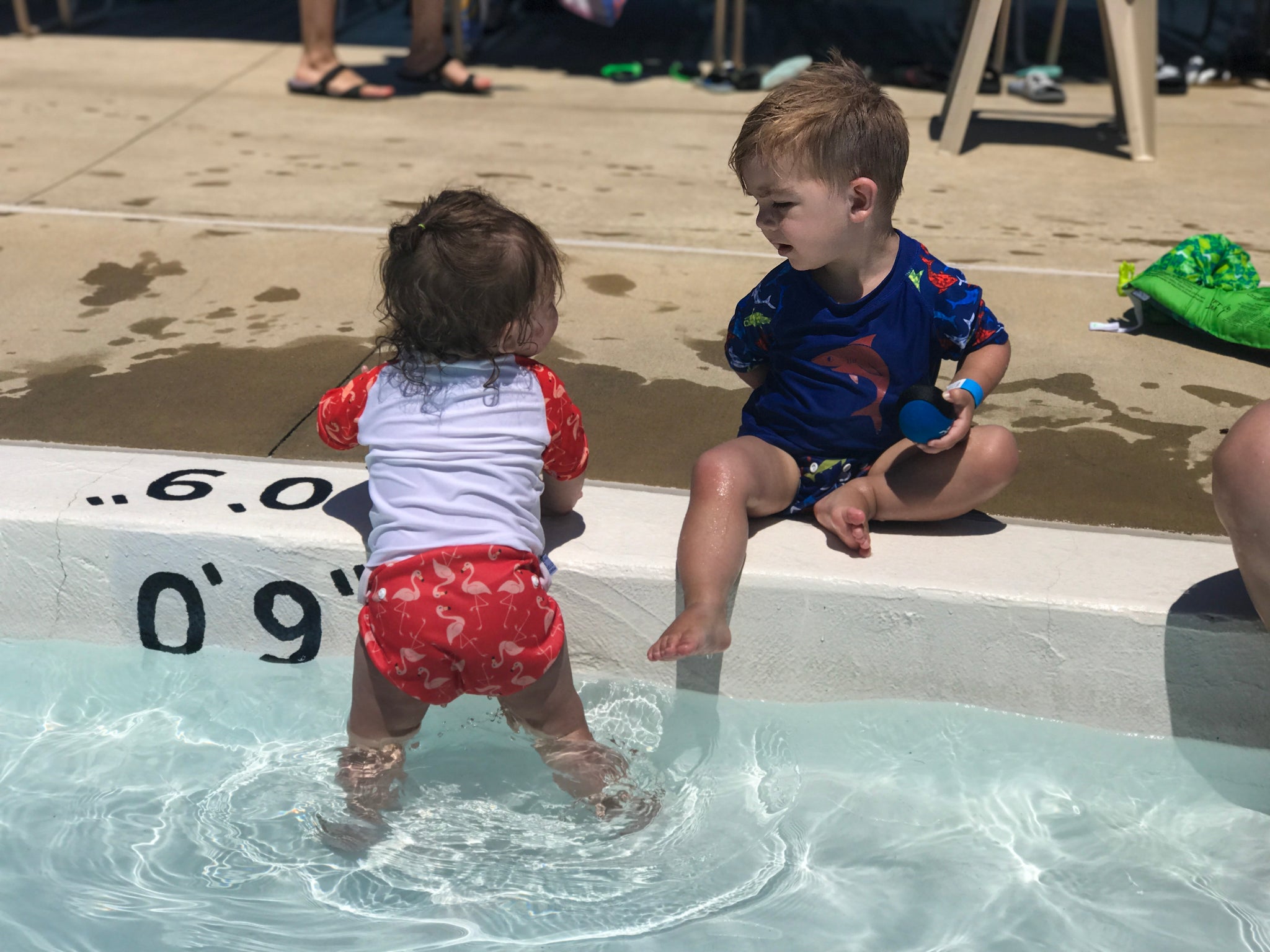 baby girl wearing a Beau and Belle Littles Rash Guard/Swim Shirt, white with pink 3/4 sleeves, flamingo print and a baby boy wearing a Beau and Belle Littles Rash Guard/Swim Shirt, dark blue with lighter blue 3/4 sleeves, shark print and matching swim diaper