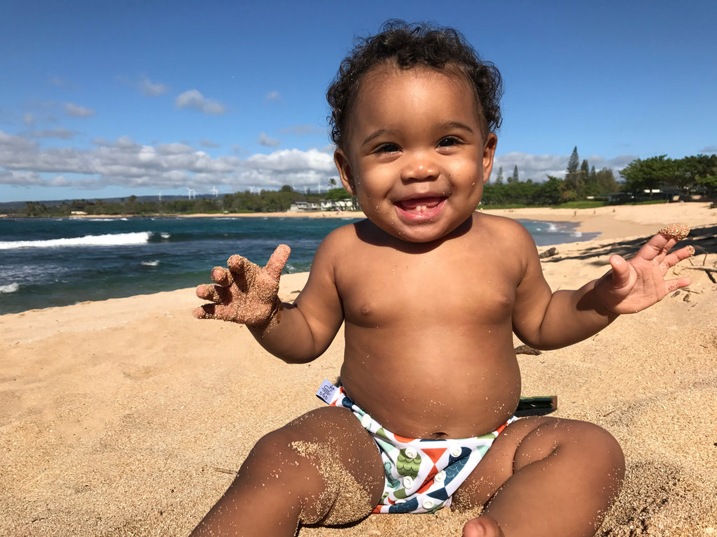 baby boy playing in the sand a the ocean smiling and wearing a Beau and Belle Littles Swim Diaper, Regular Size, fish print